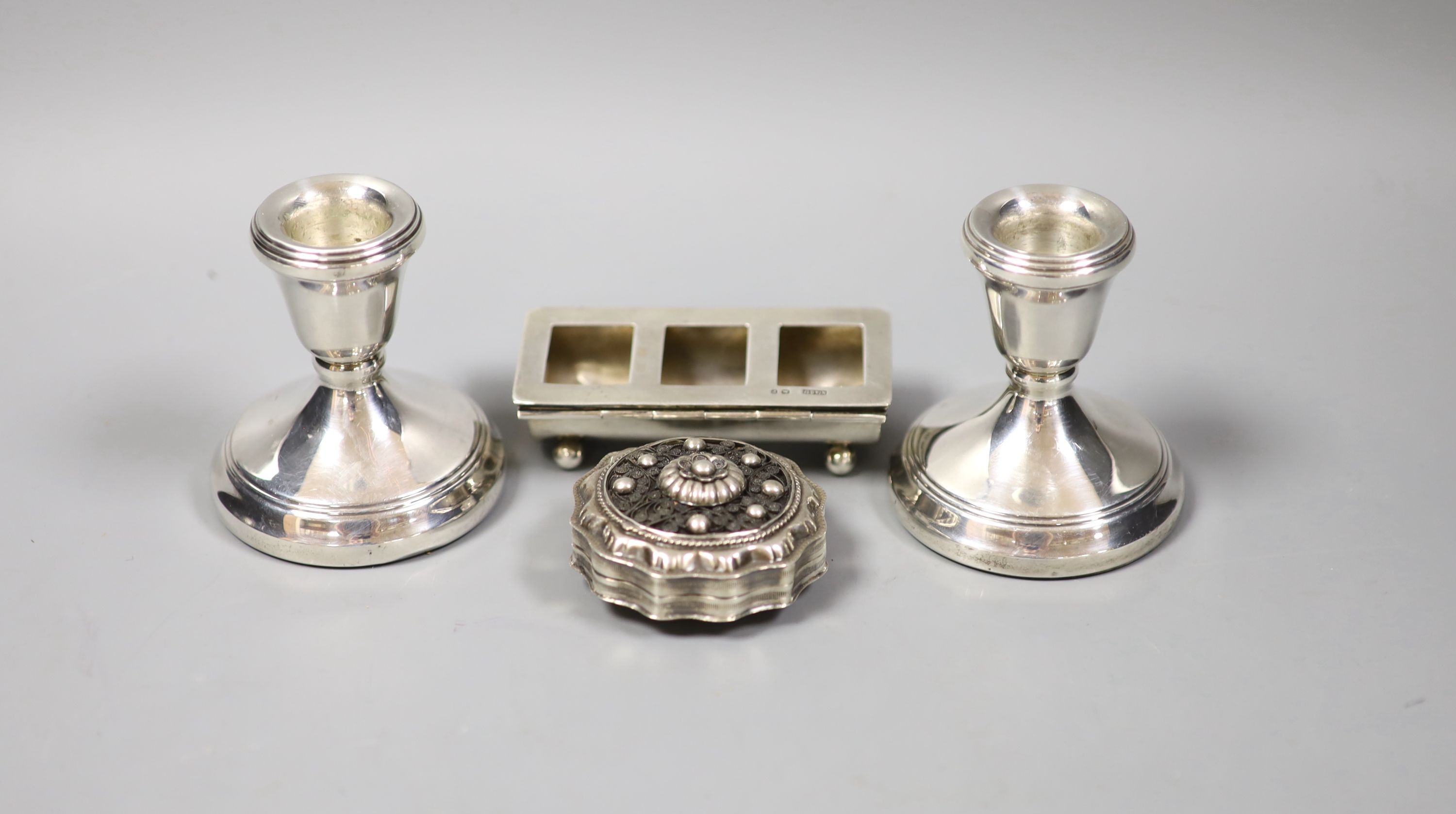 A pair of silver mounted dwarf candlesticks, 71mm, a late Victorian silver three division stamp box and a continental pill box.